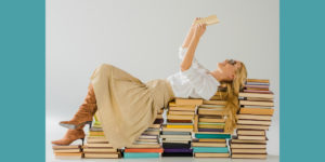 Woman lying on piles of books and reading to illustrate what readers want.