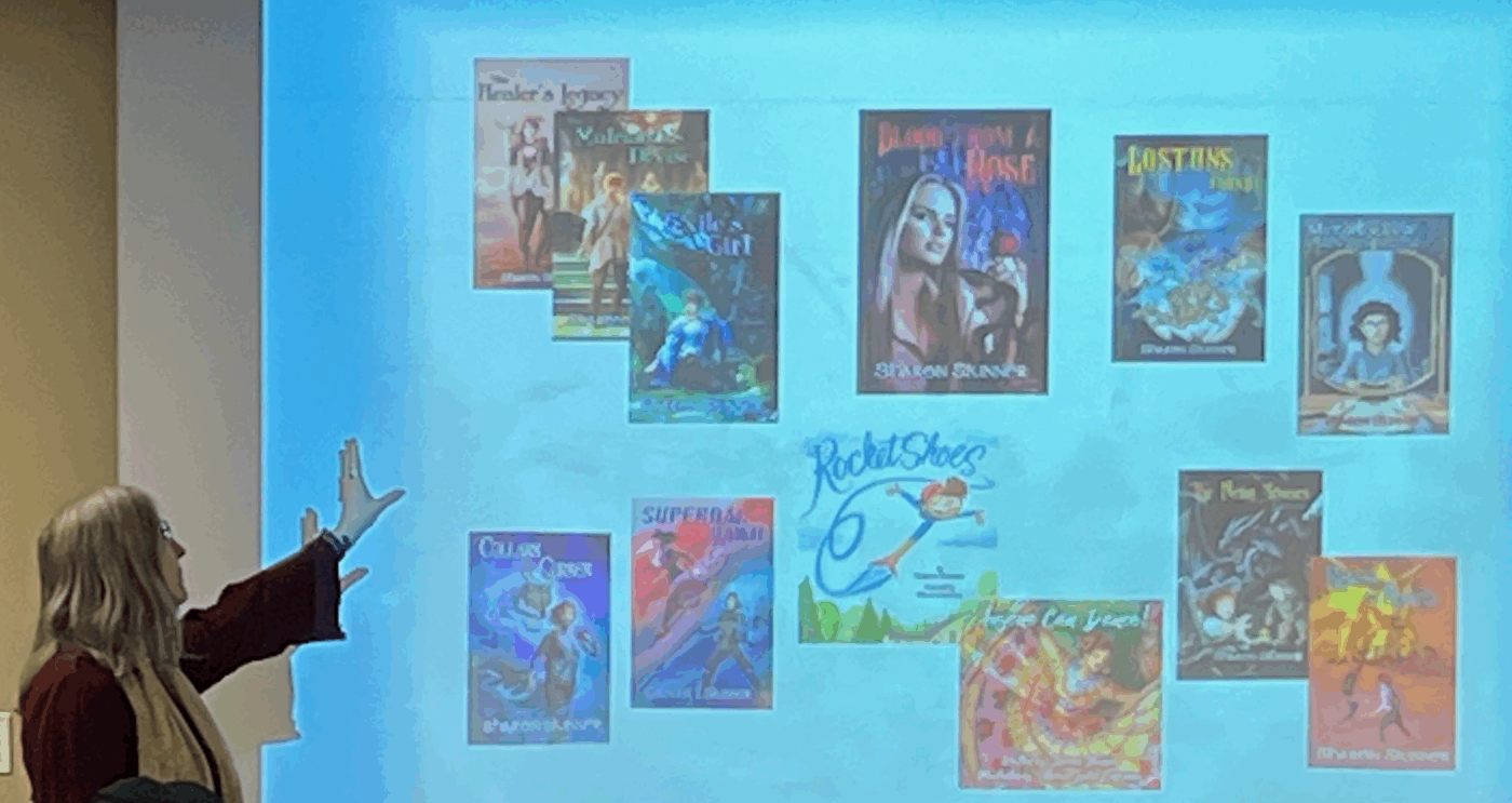 Image of sharon standing in front of a screen with her book covers projected on it as she talks about writing and publishing.